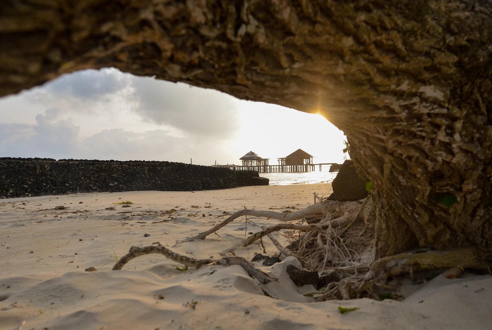 A wooden beach house on white sand under scattered clouds in Samoa