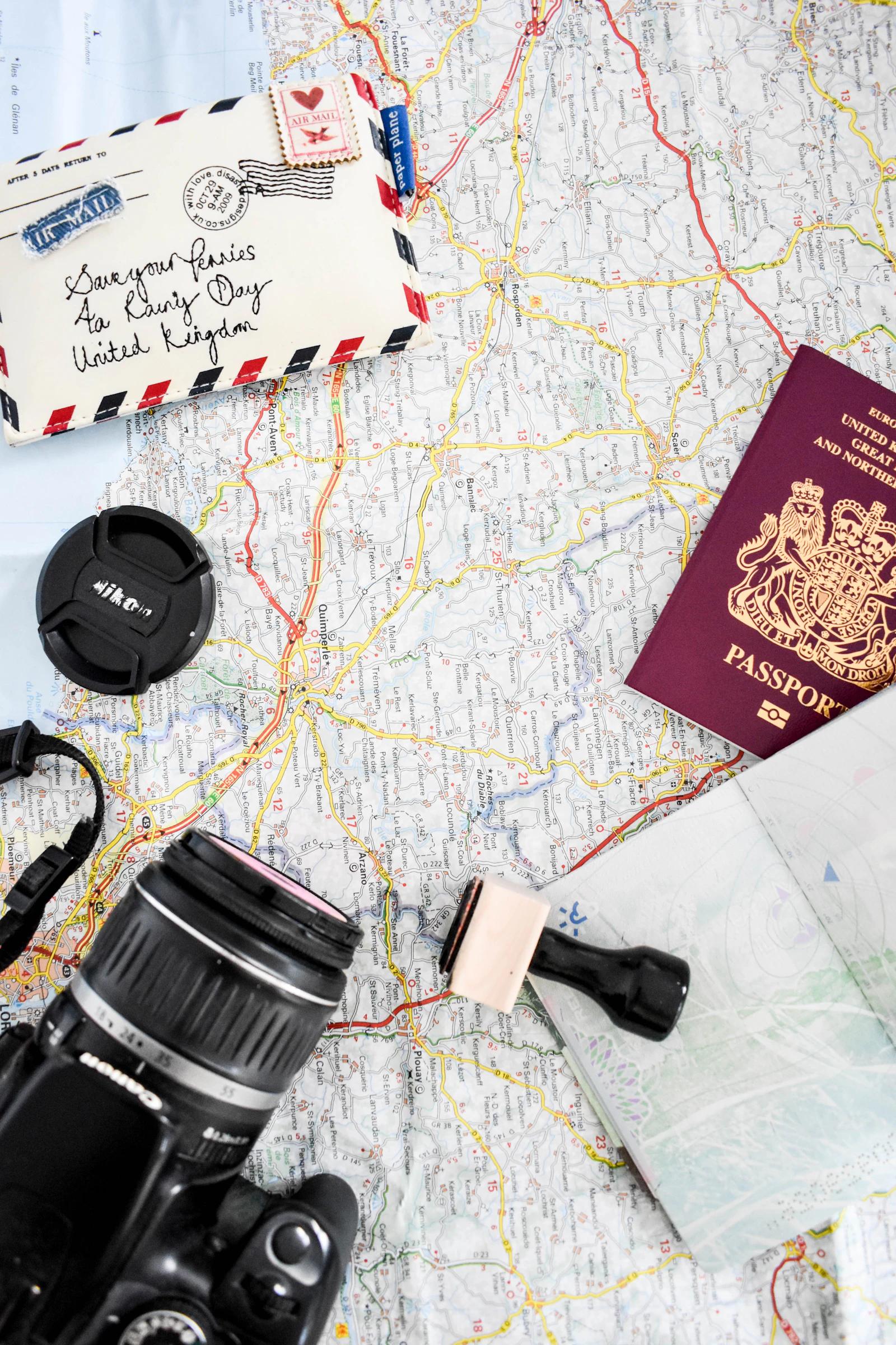 A map, camera, passport and other travel items on a table