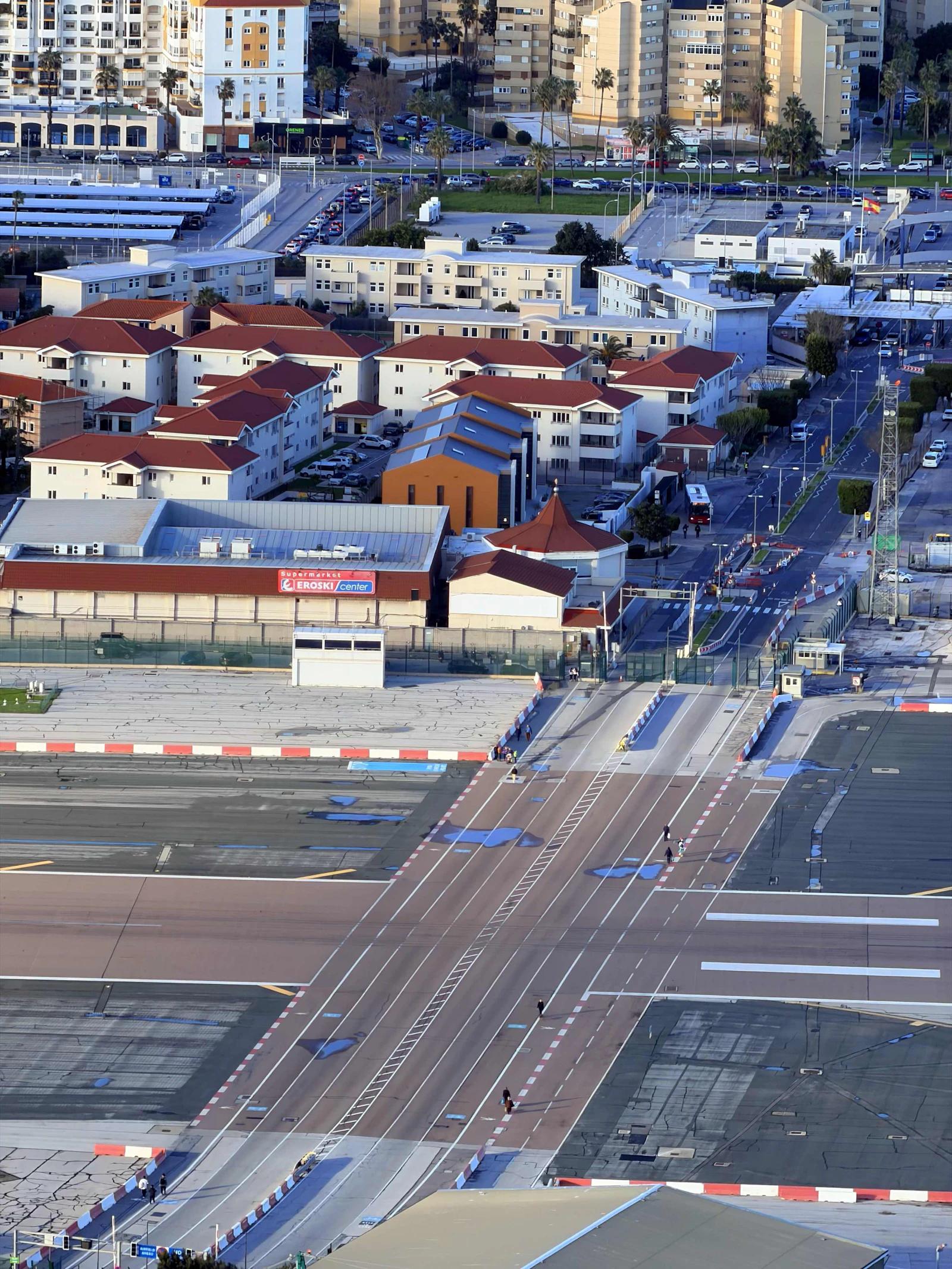 Vista aérea da pista do aeroporto de Gibraltar cruzando uma estrada, com a baía ao lado